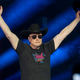 Elon Musks Dumb Elden Ring Build prouve que le milliardaire est sans jeune fille 1 Elon Musk à la soirée d'ouverture de Tesla Giga Texas vêtu d'un t-shirt noir, d'un chapeau de cowboy noir et de lunettes de soleil noires, les bras levés en signe de célébration.